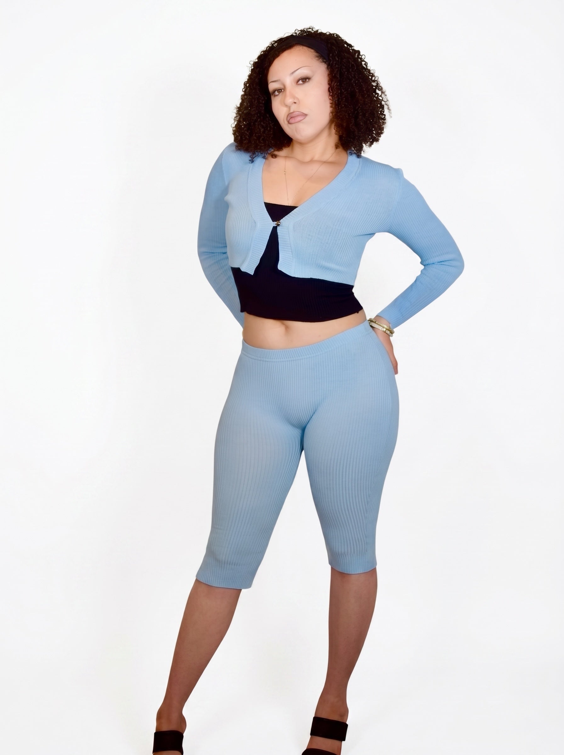 Woman wearing a light blue outfit with a black top and shorts on a white background
