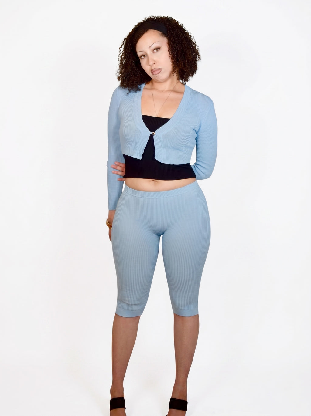 Woman wearing a light blue outfit with a black top on a white background