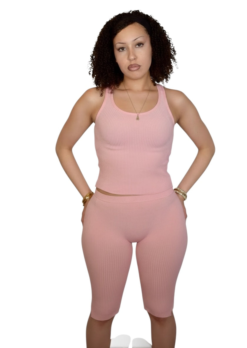 Woman wearing a pink tank top and shorts set on a white background