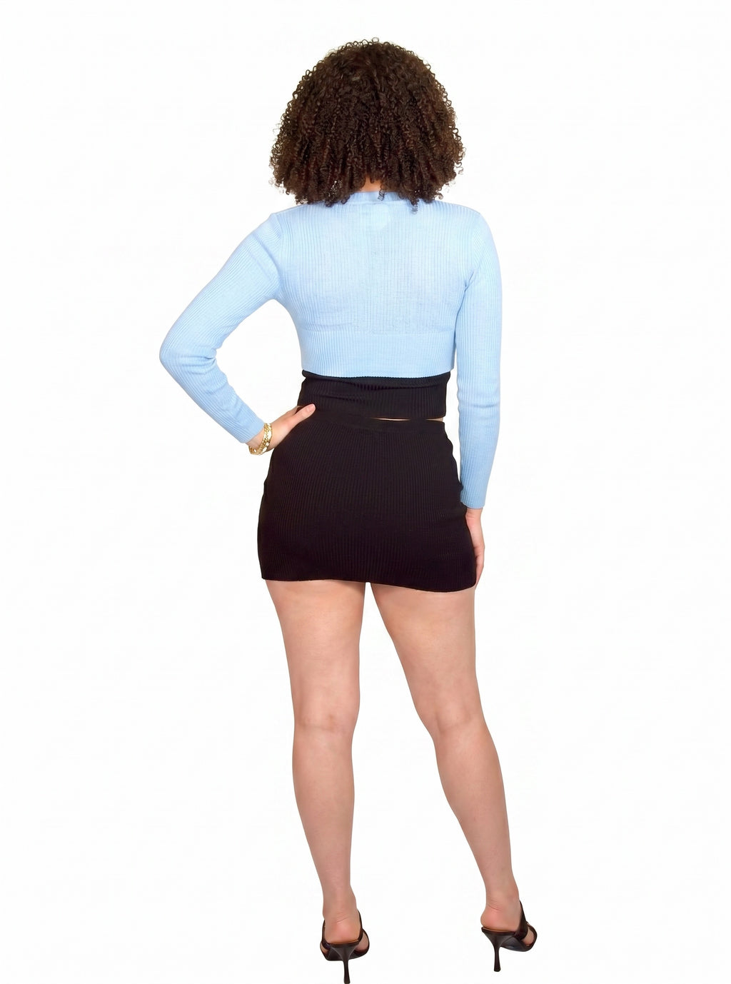 Person wearing a light blue long-sleeve top and black skirt on a white background