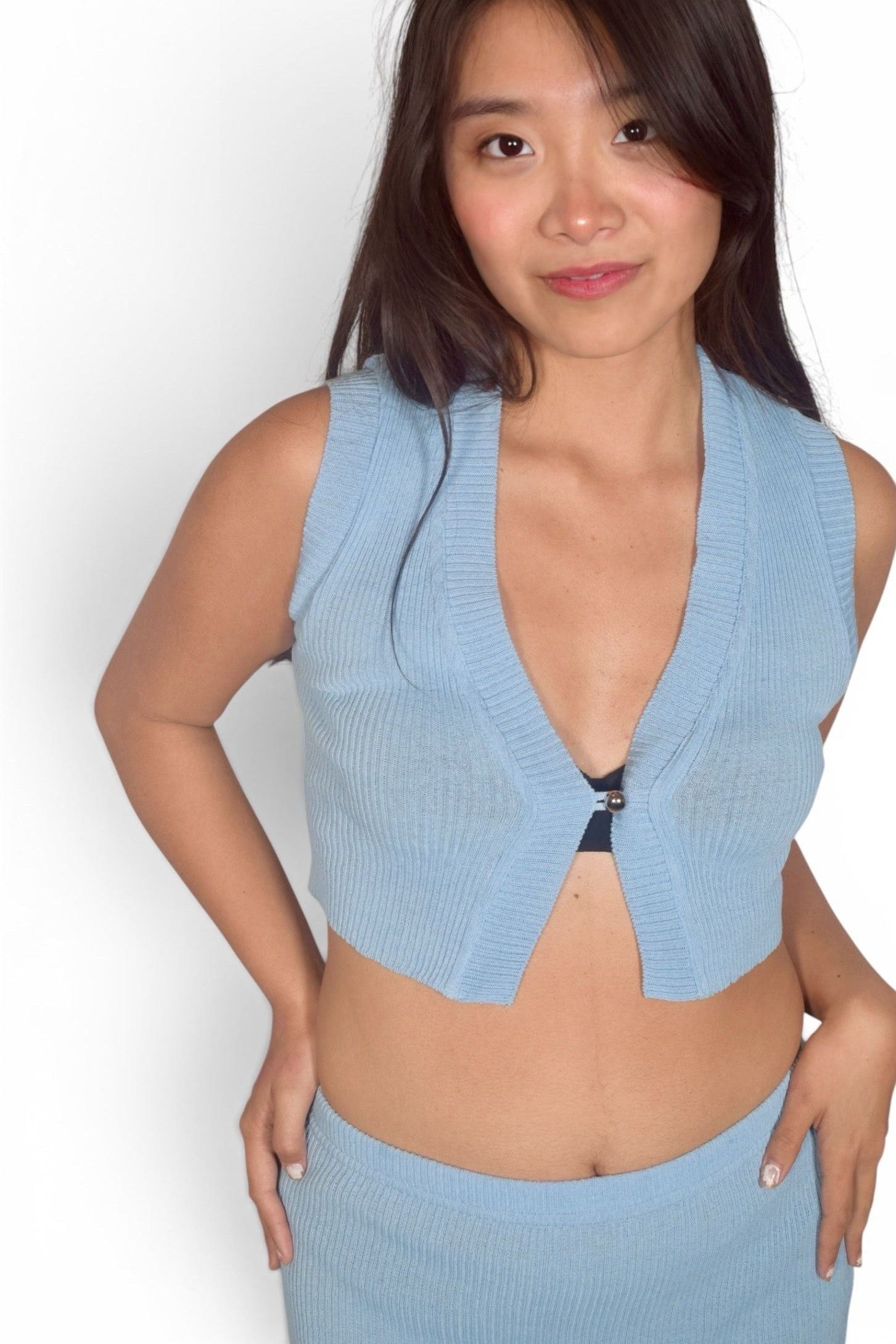 Woman wearing a light blue sleeveless top against a white background
