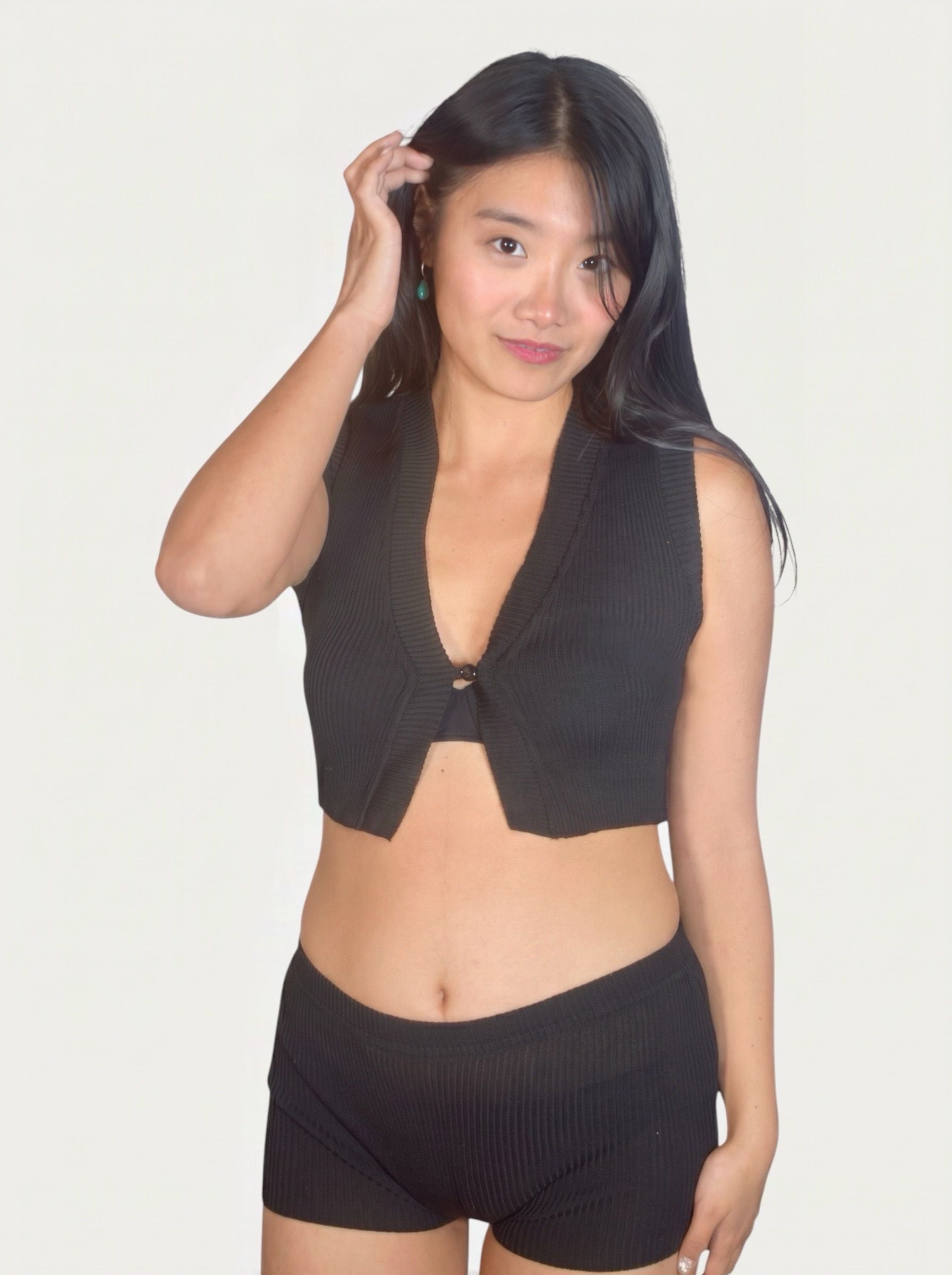 Woman wearing a black sleeveless top and shorts on a plain background