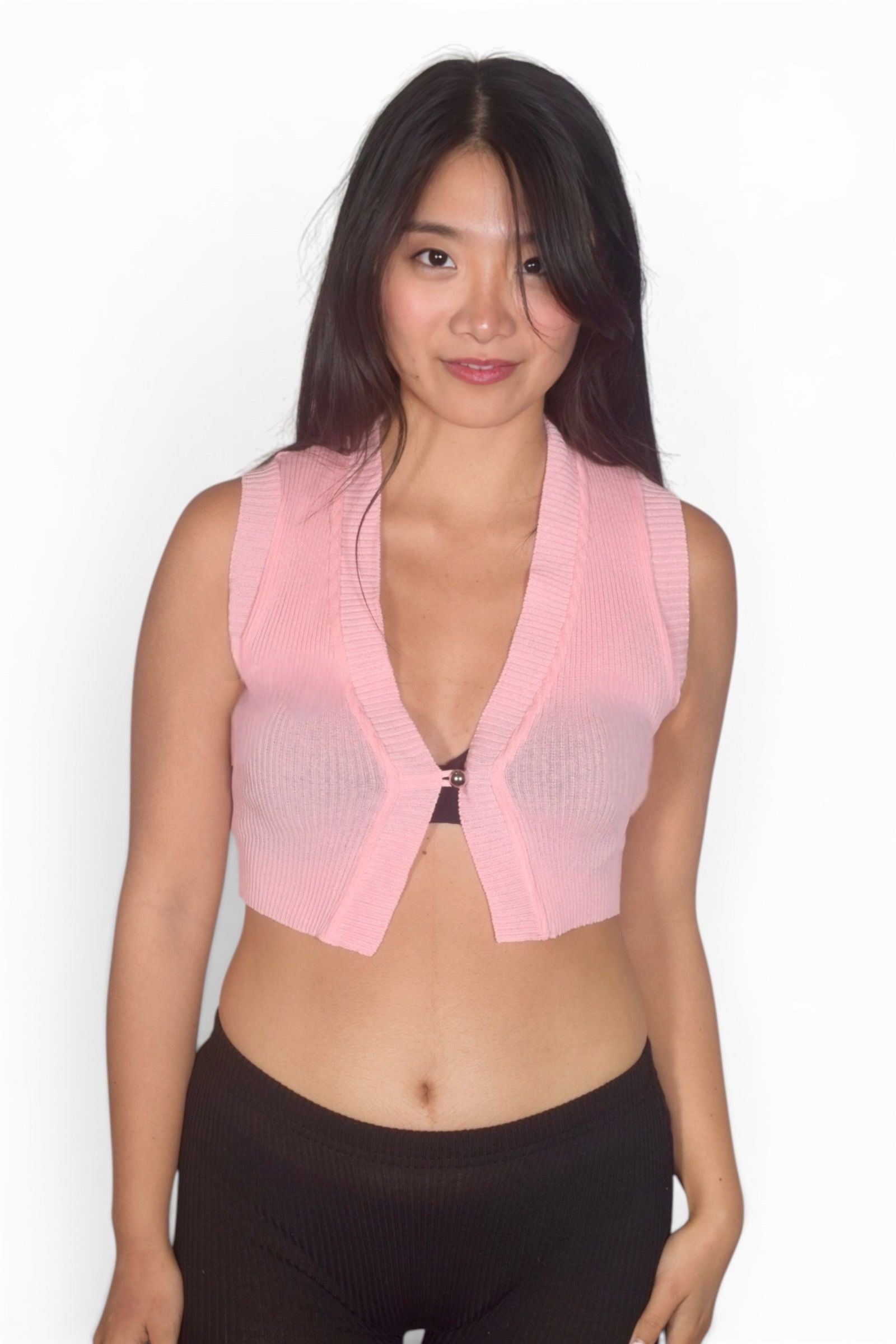 Woman wearing a pink mesh top over a black sports bra on a white background