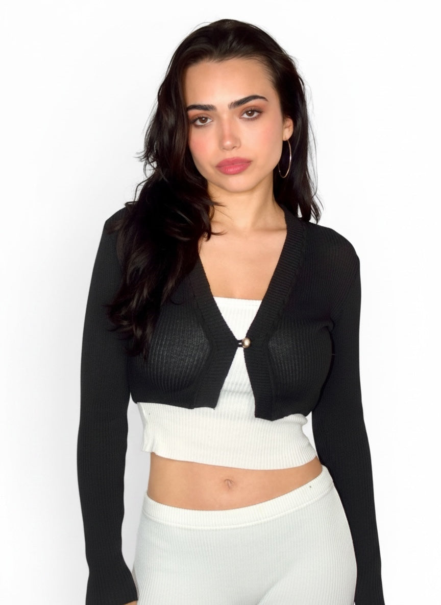 Woman wearing a black cardigan over a white top and pants on a white background