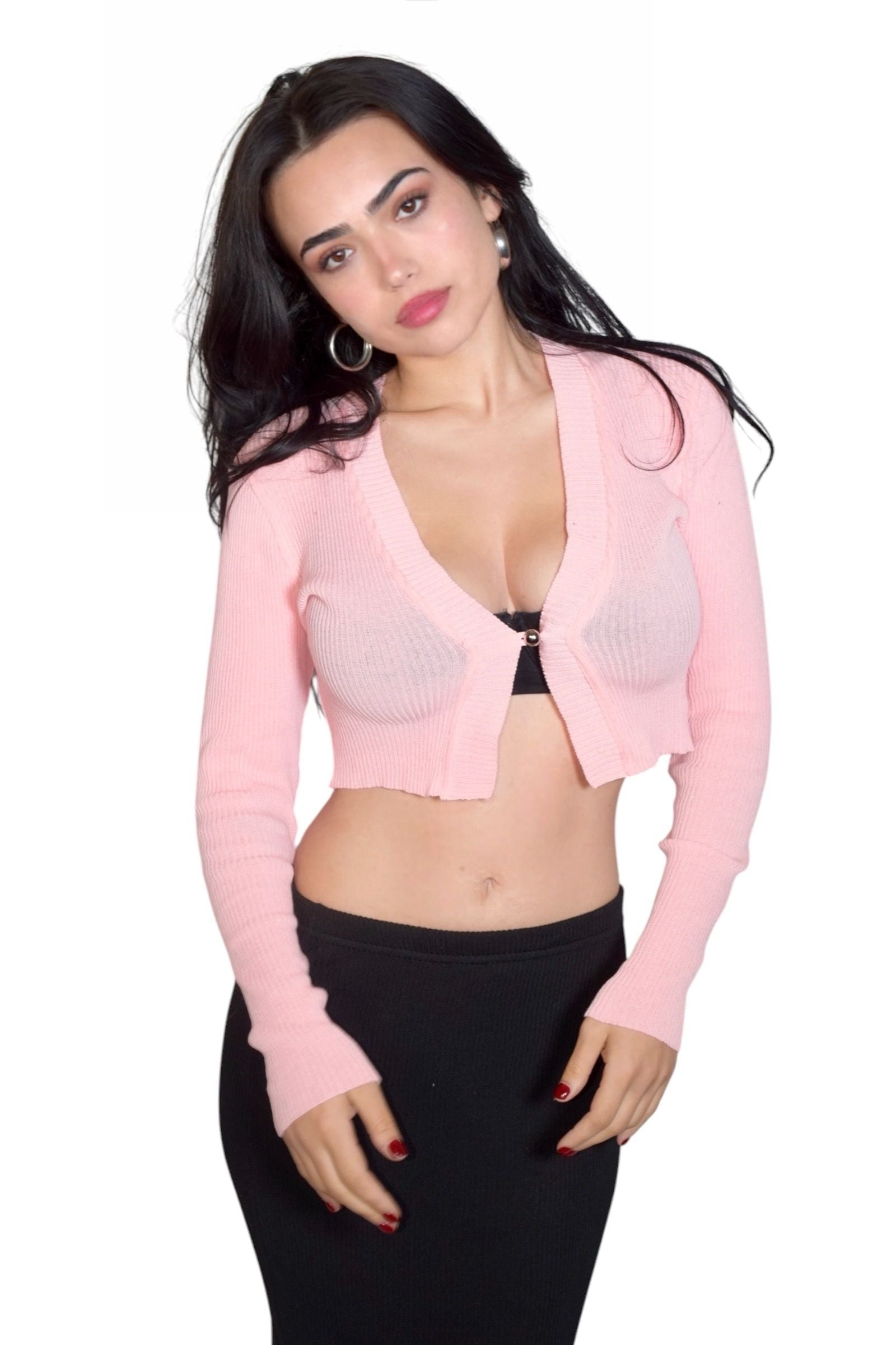 Woman wearing a pink cardigan over a black bra and pants on a white background