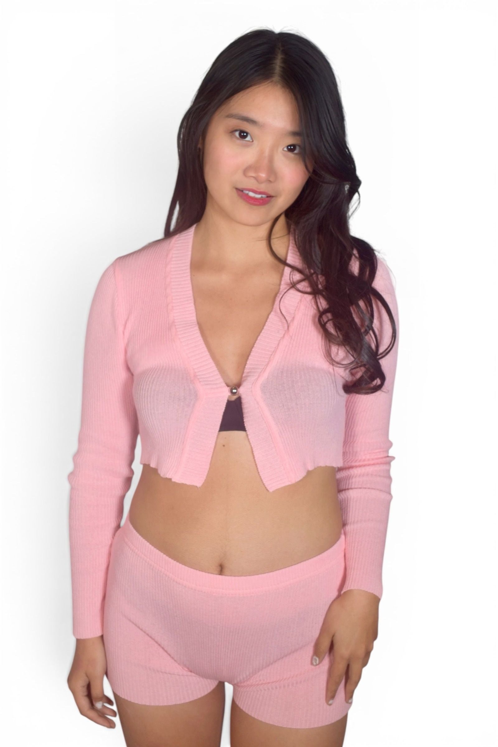 Woman wearing a pink outfit with a sheer top on a white background