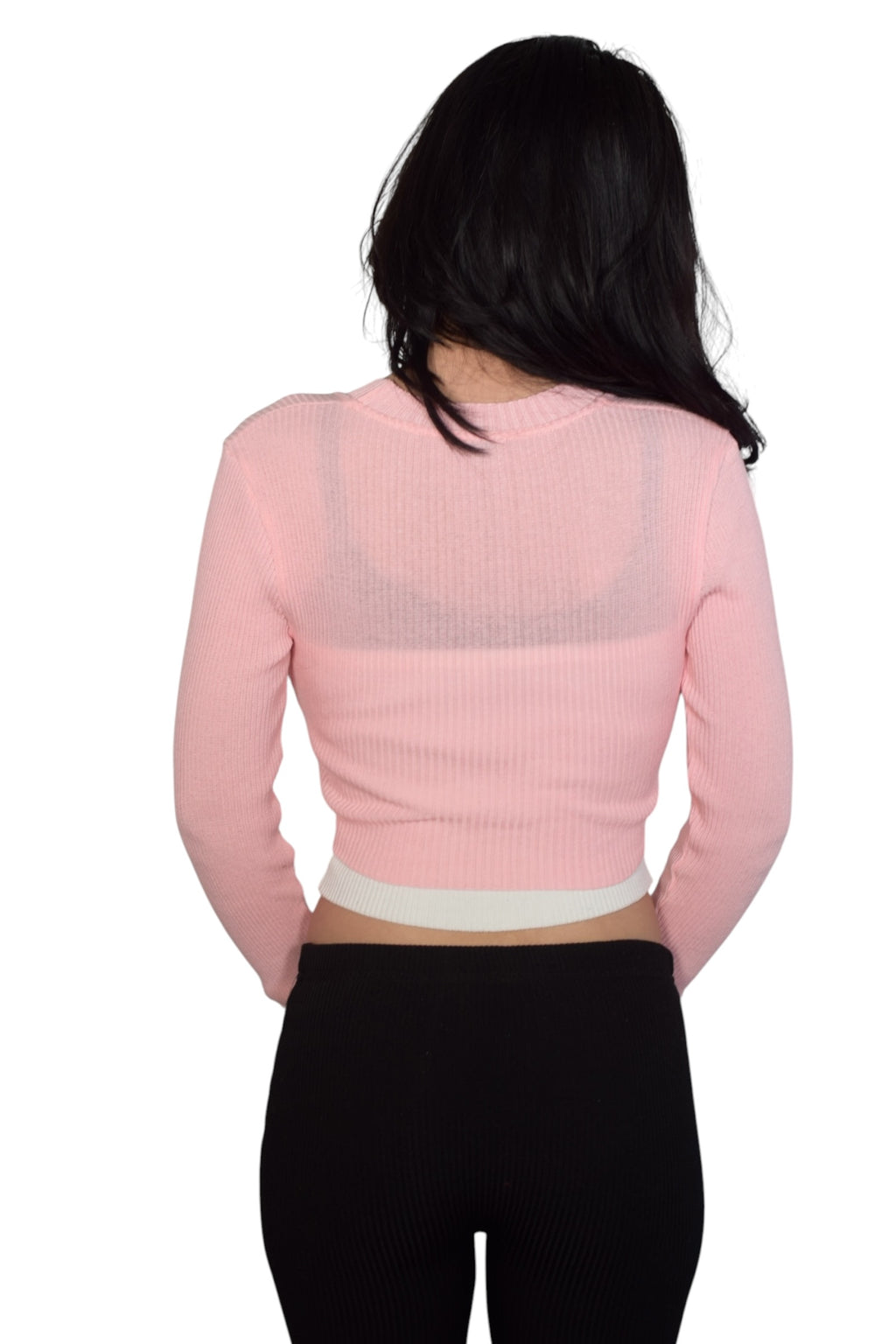 Person wearing a pink cropped shrug over white cami w black straps on a white background