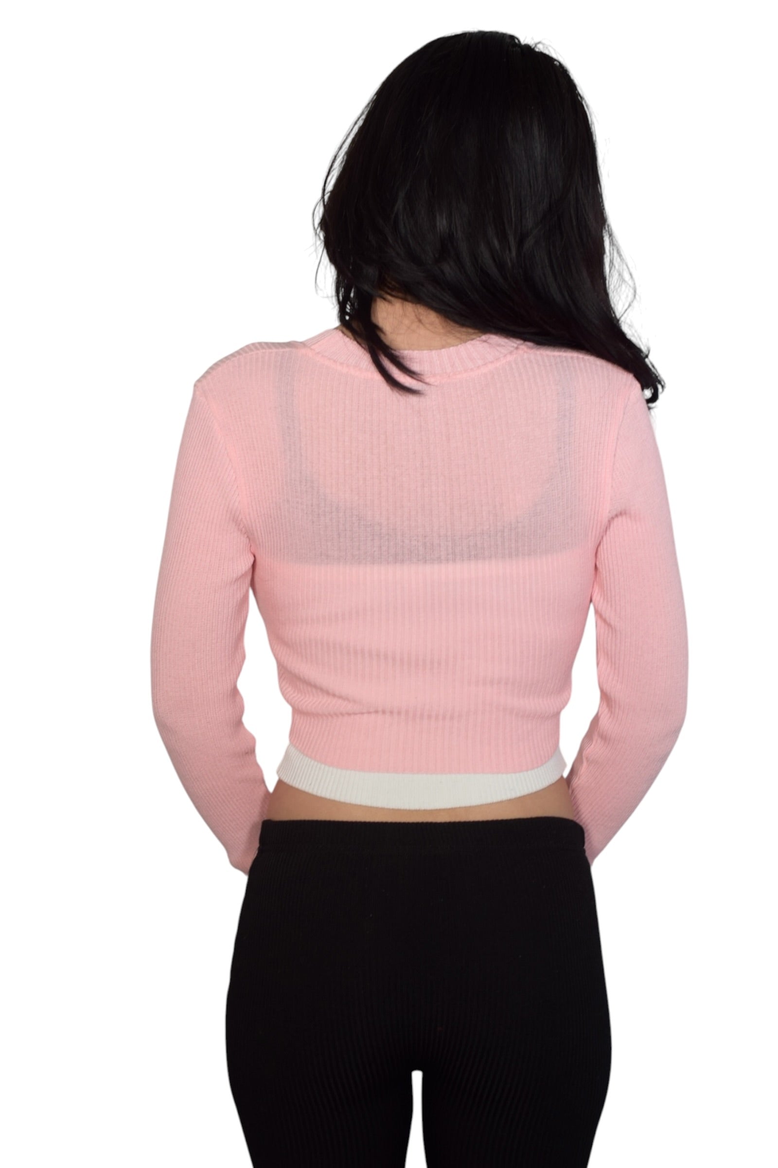 Person wearing a pink cropped shrug over white cami w black straps on a white background