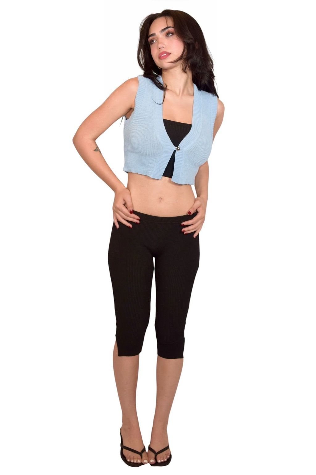 Woman wearing a light blue crop top and black capri pants on a white background