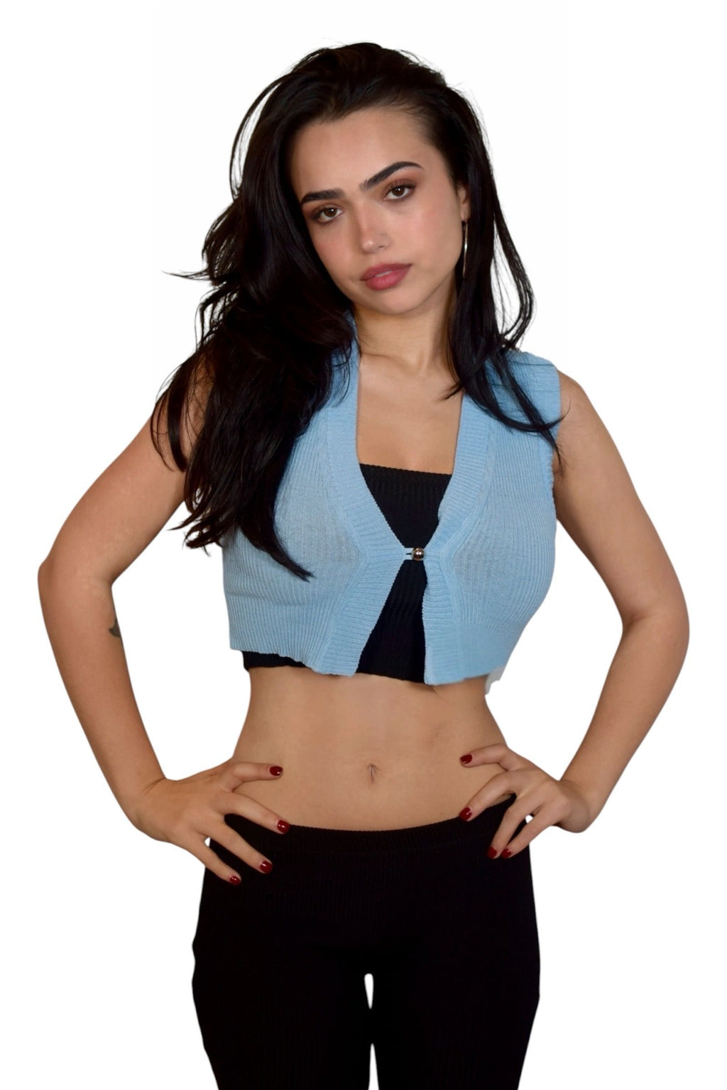 Woman wearing a light blue sleeveless cardigan over a black top on a white background