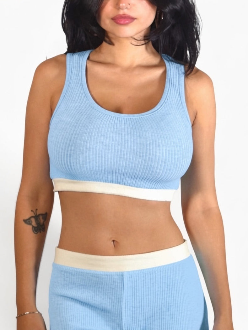 Woman wearing a light blue and white sports bra and leggings set on a plain background
