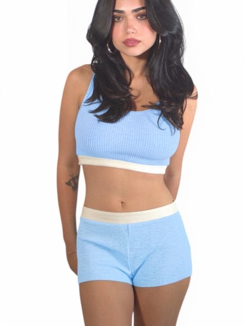 Woman wearing a light blue sports bra and shorts set on a white background