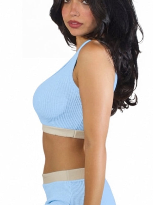 Woman wearing a light blue sports bra and shorts on a white background