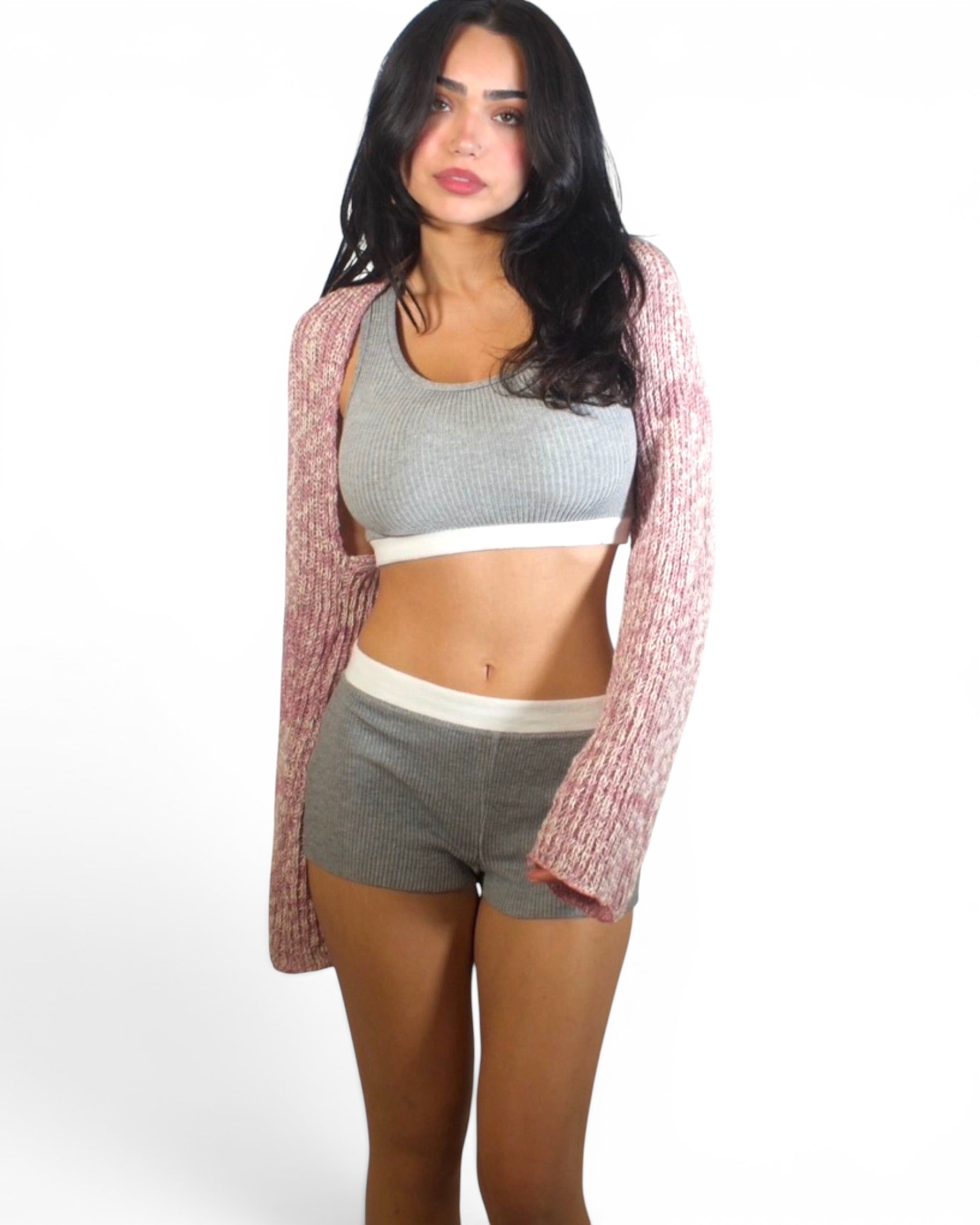 Woman wearing mist tank and short with pink shrug by TKHLA. 