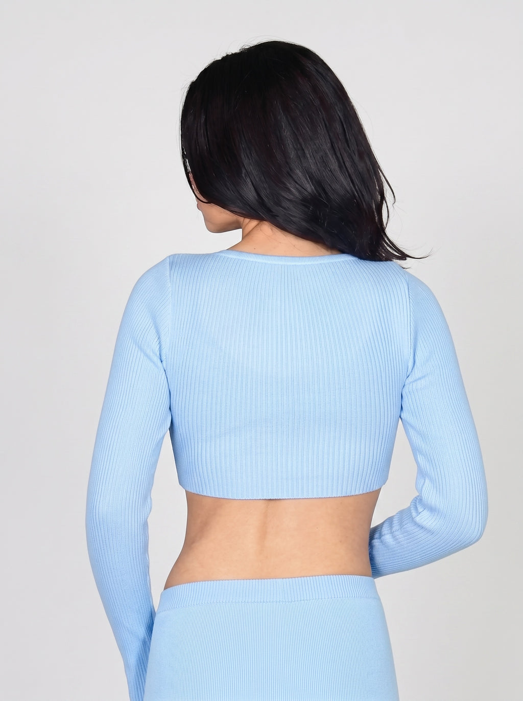 Back view of person wearing soft blue rib knit crop long sleeve top and skirt by TKHLA