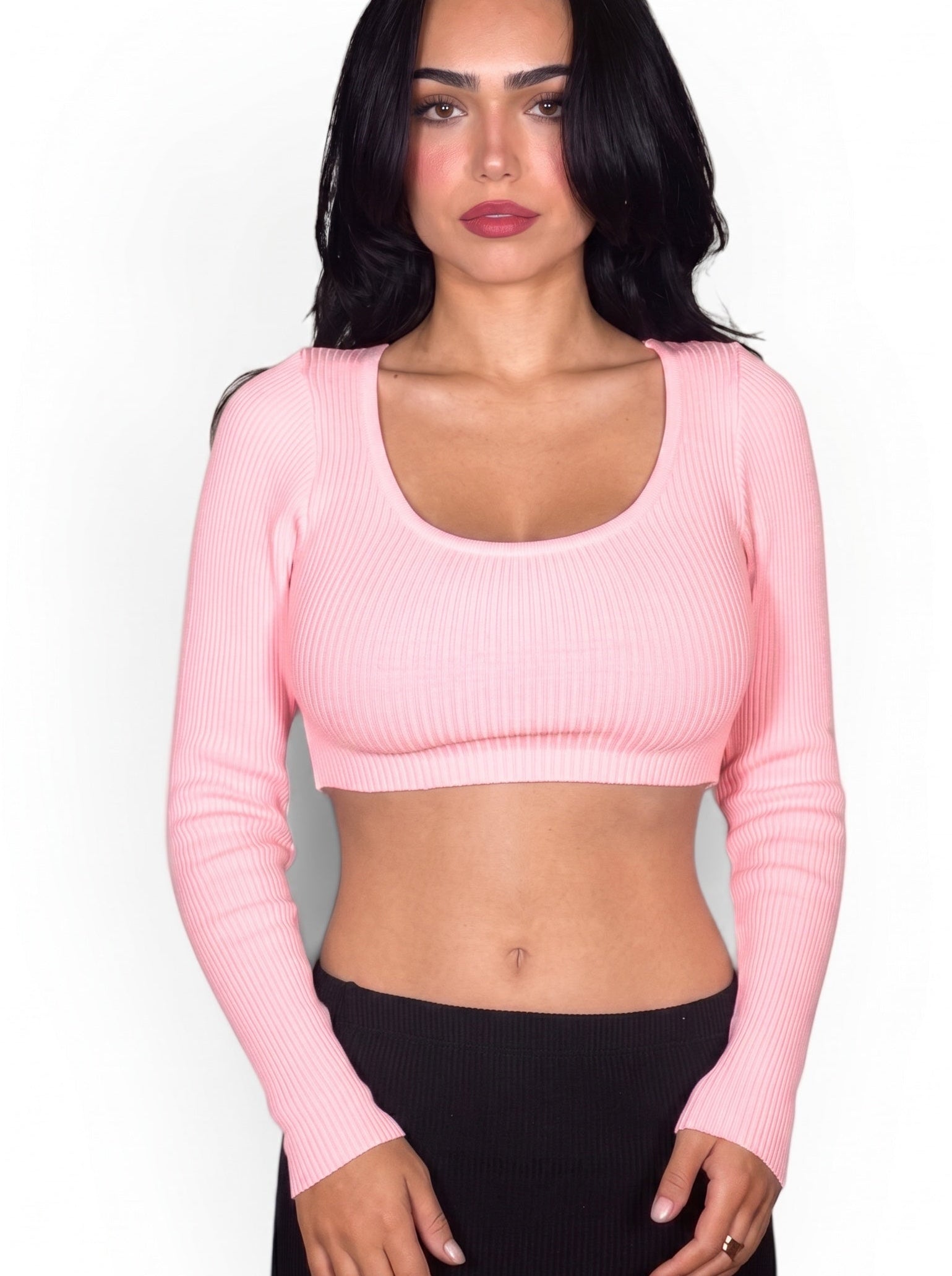 Woman wearing a pink long-sleeve crop top against a white background