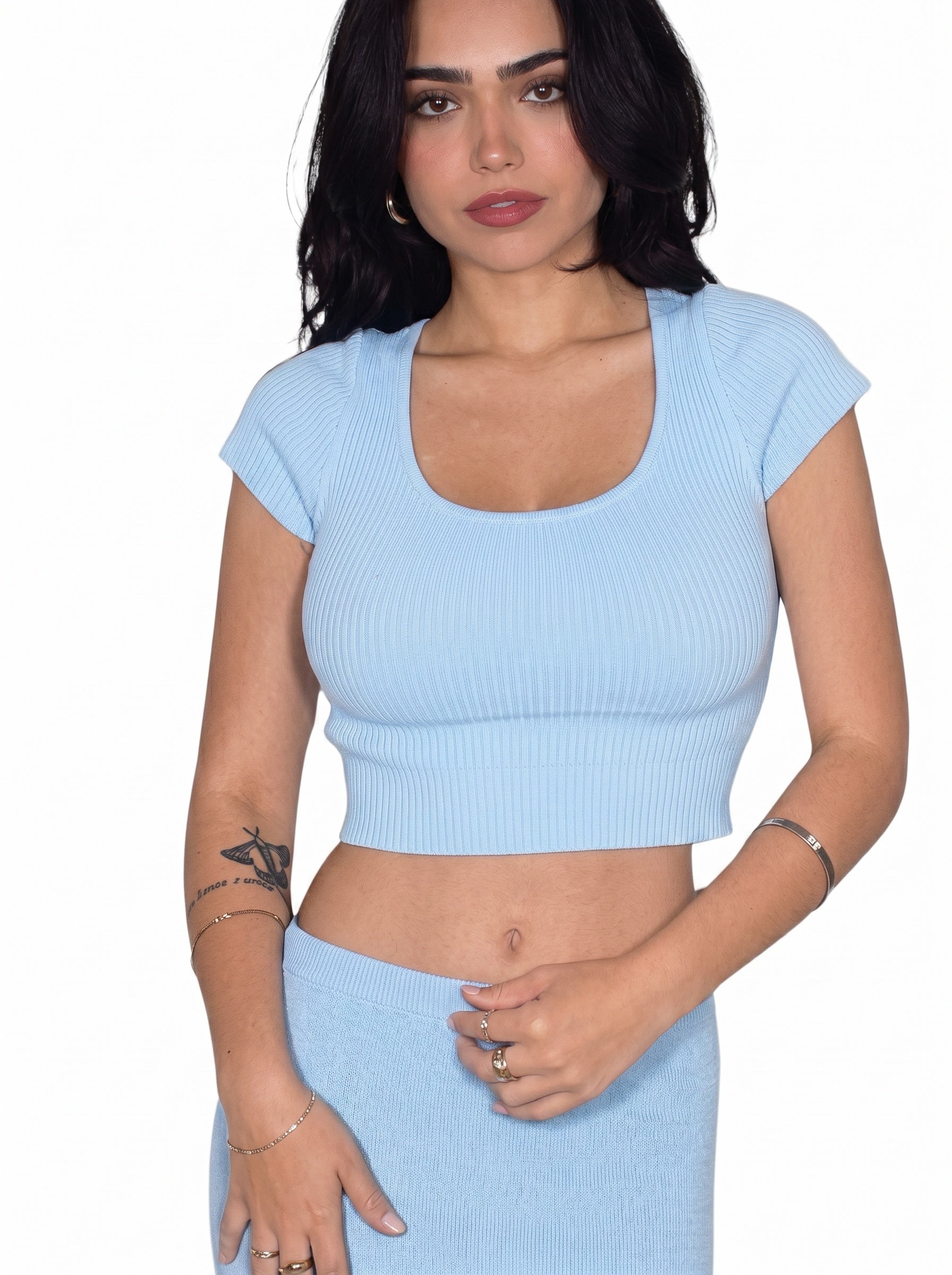 Woman wearing a light blue ribbed crop top and skirt set on a white background