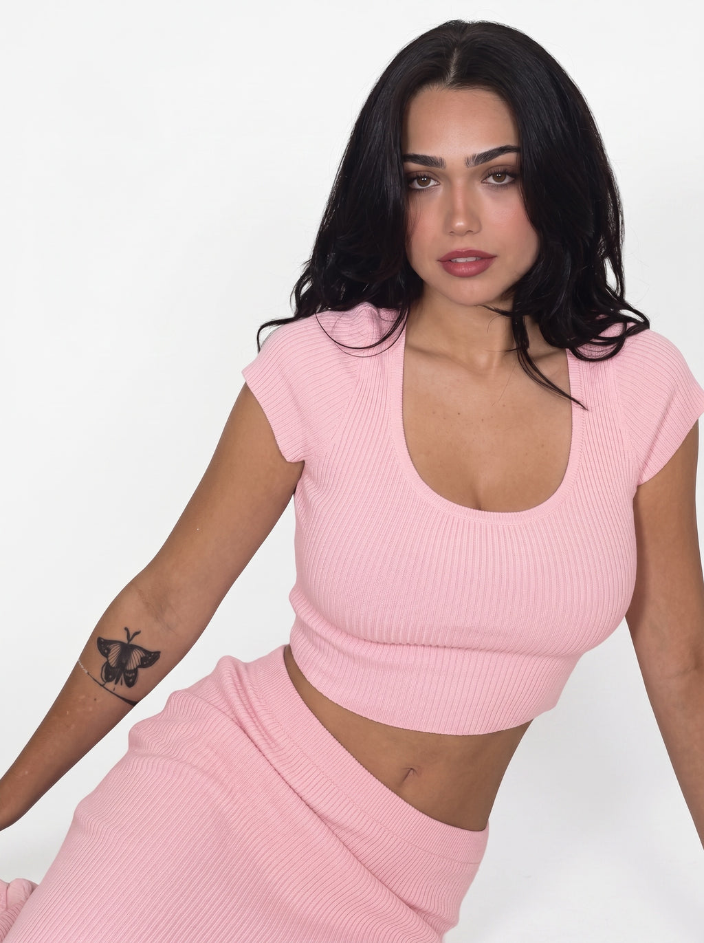 Woman sitting in pink rib knit crop top and matching long skirt by TKHLA