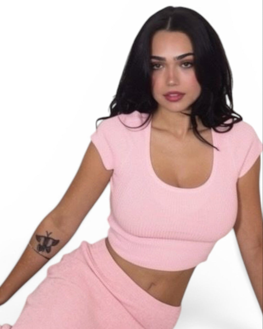 Woman wearing a pink outfit sitting on a white background