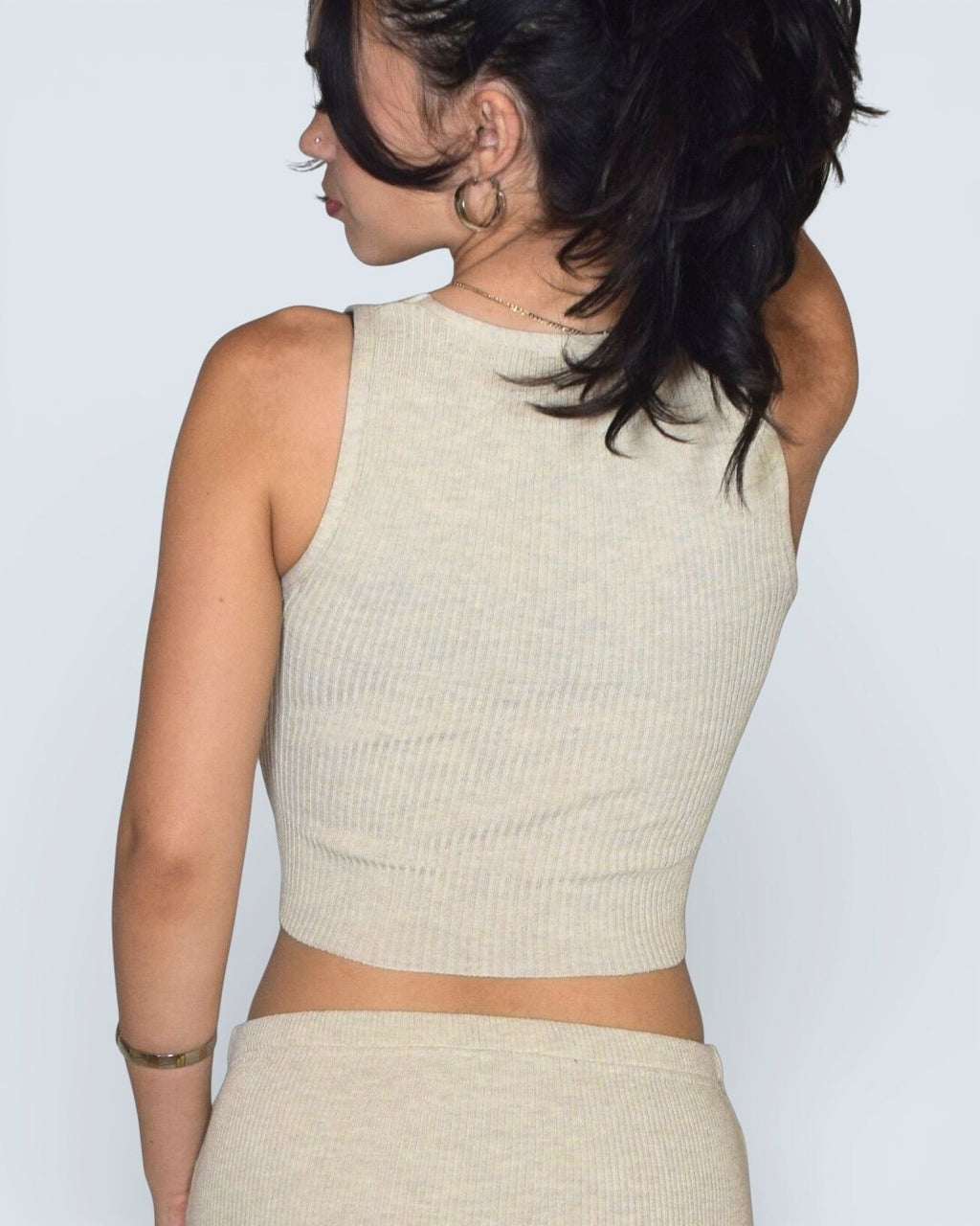 Woman wearing a beige tank top against a plain background
