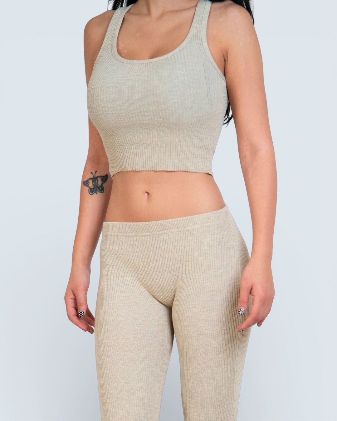 Person wearing a drift beige ribbed scoop-neck tank top and leggings against a light gray background