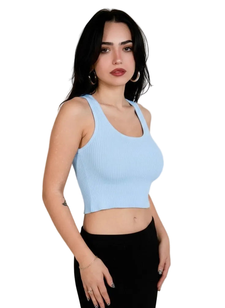 Woman wearing a light blue crop top and black pants against a plain background
