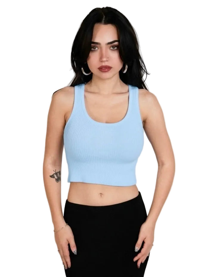 Woman wearing a light blue tank top and black pants against a plain background