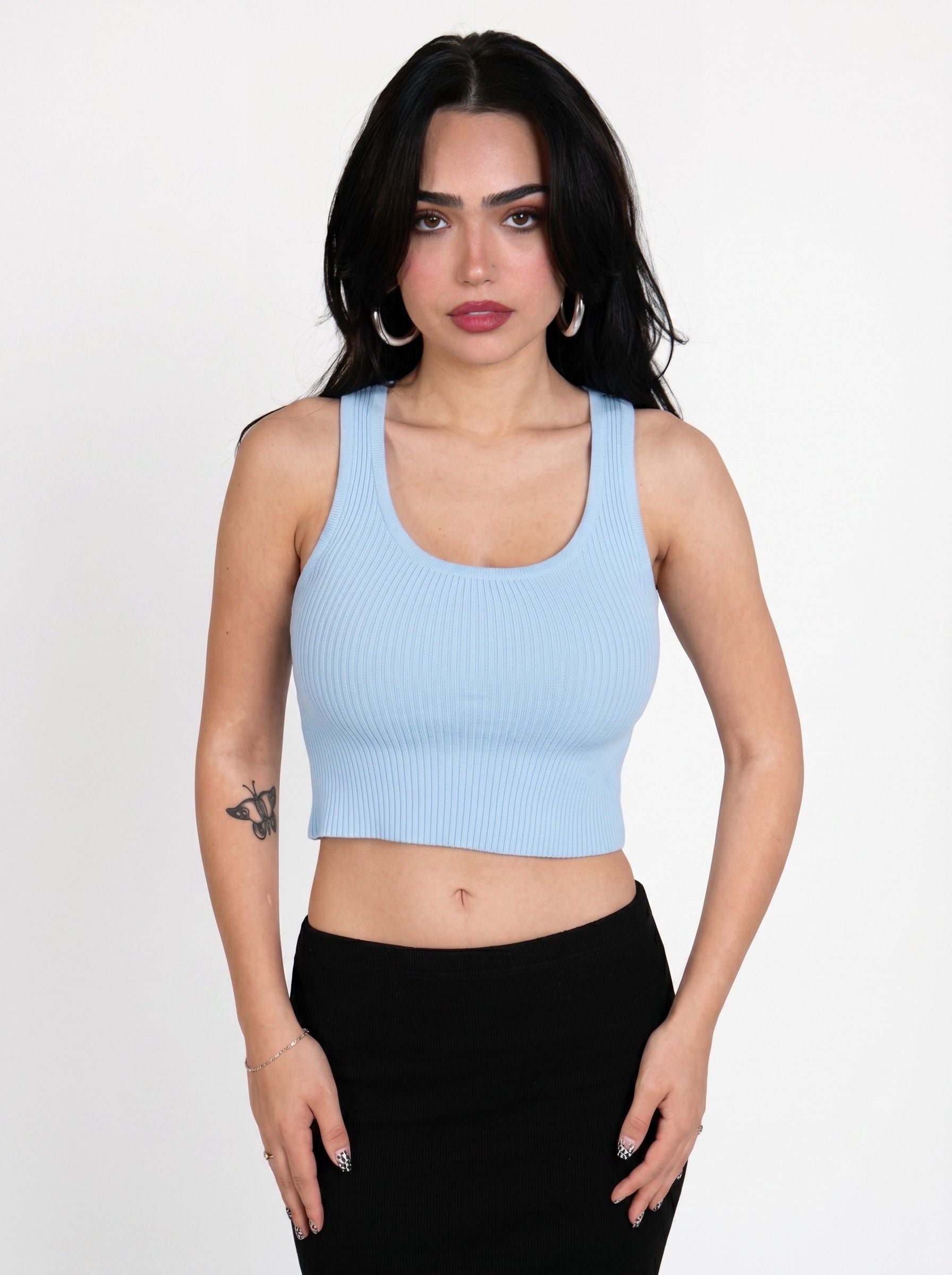 Woman wearing soft blue rib knit scoop neck crop tank and black skirt by TKHLA