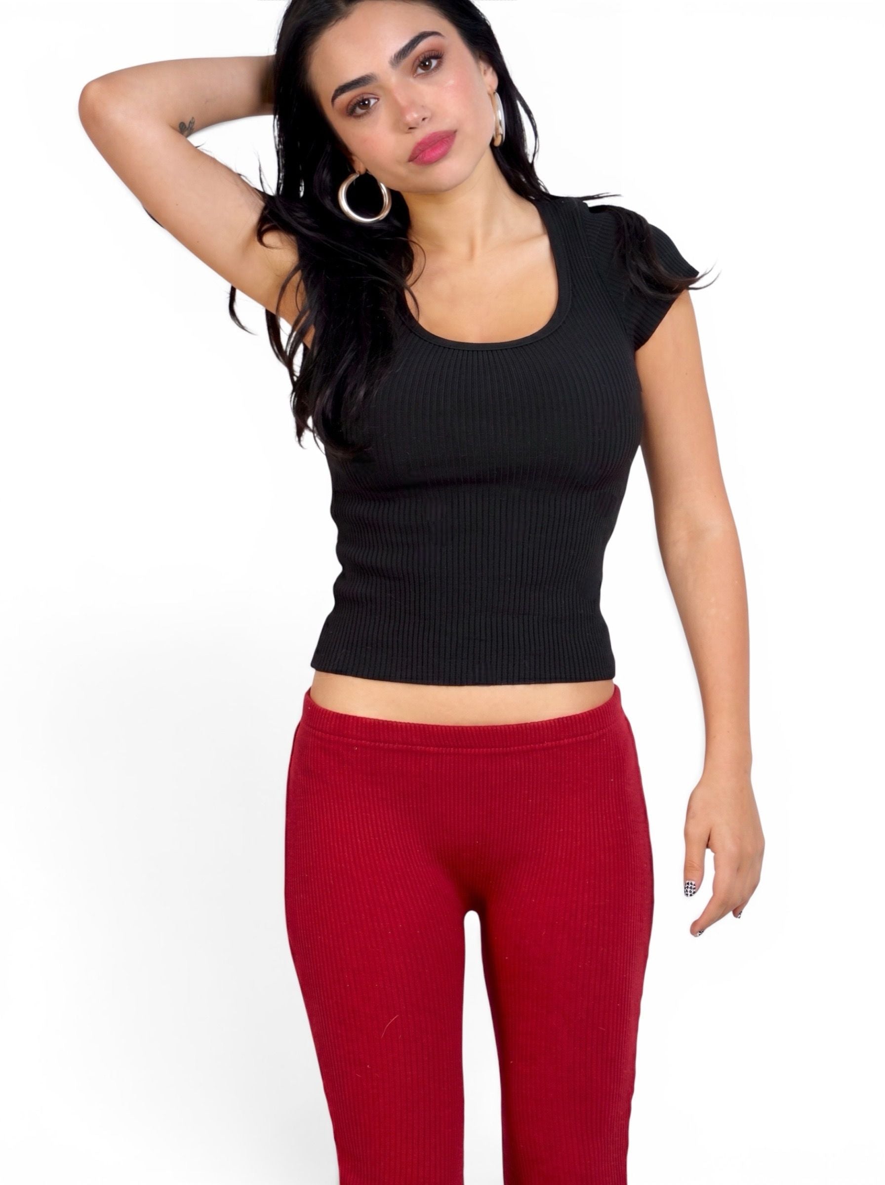 Woman wearing black rib knit short sleeve scoop neck top and red capris by TKHLA 