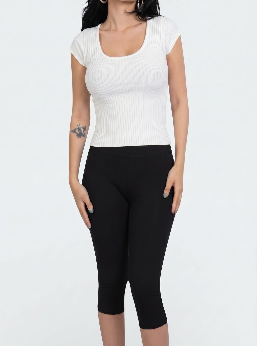 Woman wearing short sleeve white rib knit scoop neck top and black capris by TKHLA 