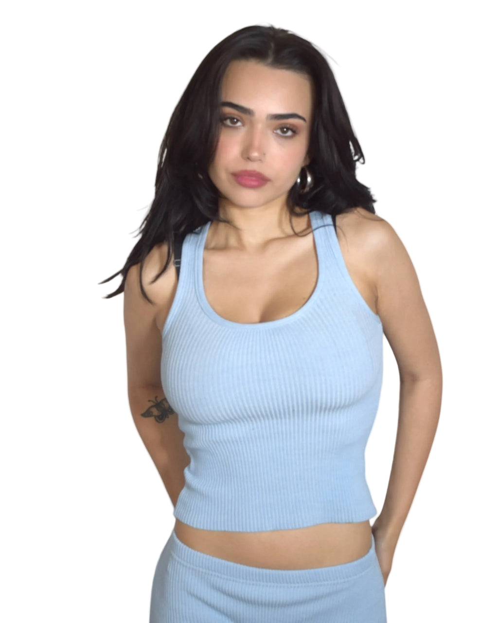 Woman wearing a light blue ribbed tank top against a plain background