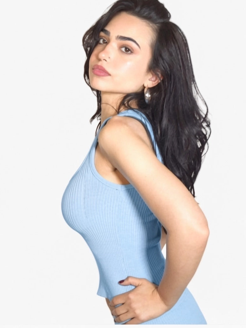 Woman wearing a light blue sleeveless top against a white background