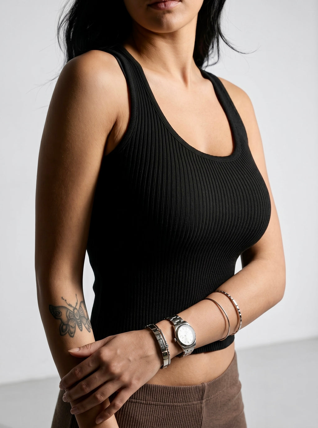 Woman wearing black rib knit scoop neck tank and brown rib pant. 