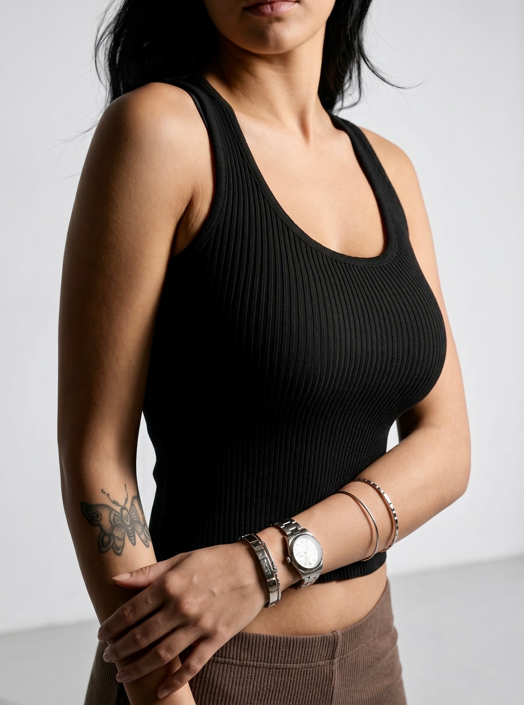 Woman wearing black rib knit scoop neck tank and brown rib pant. 