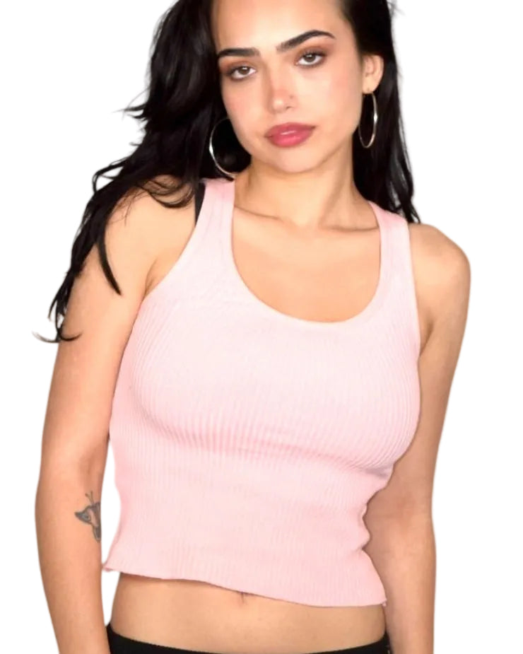Woman wearing a pink tank top and black capri pants on a white background