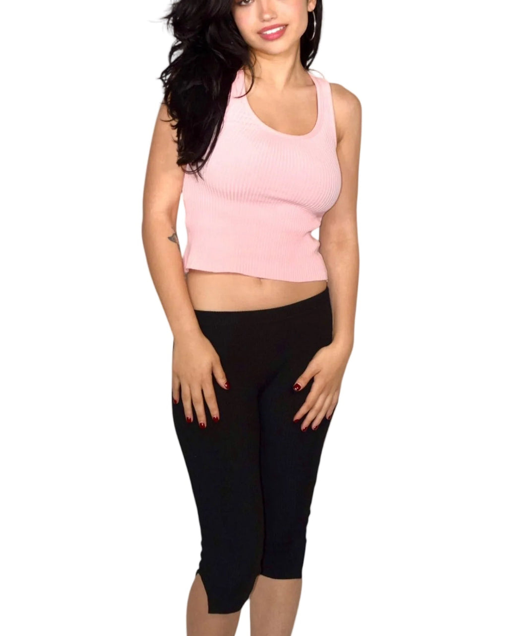 Woman wearing a pink sleeveless top and black capri pants on a white background
