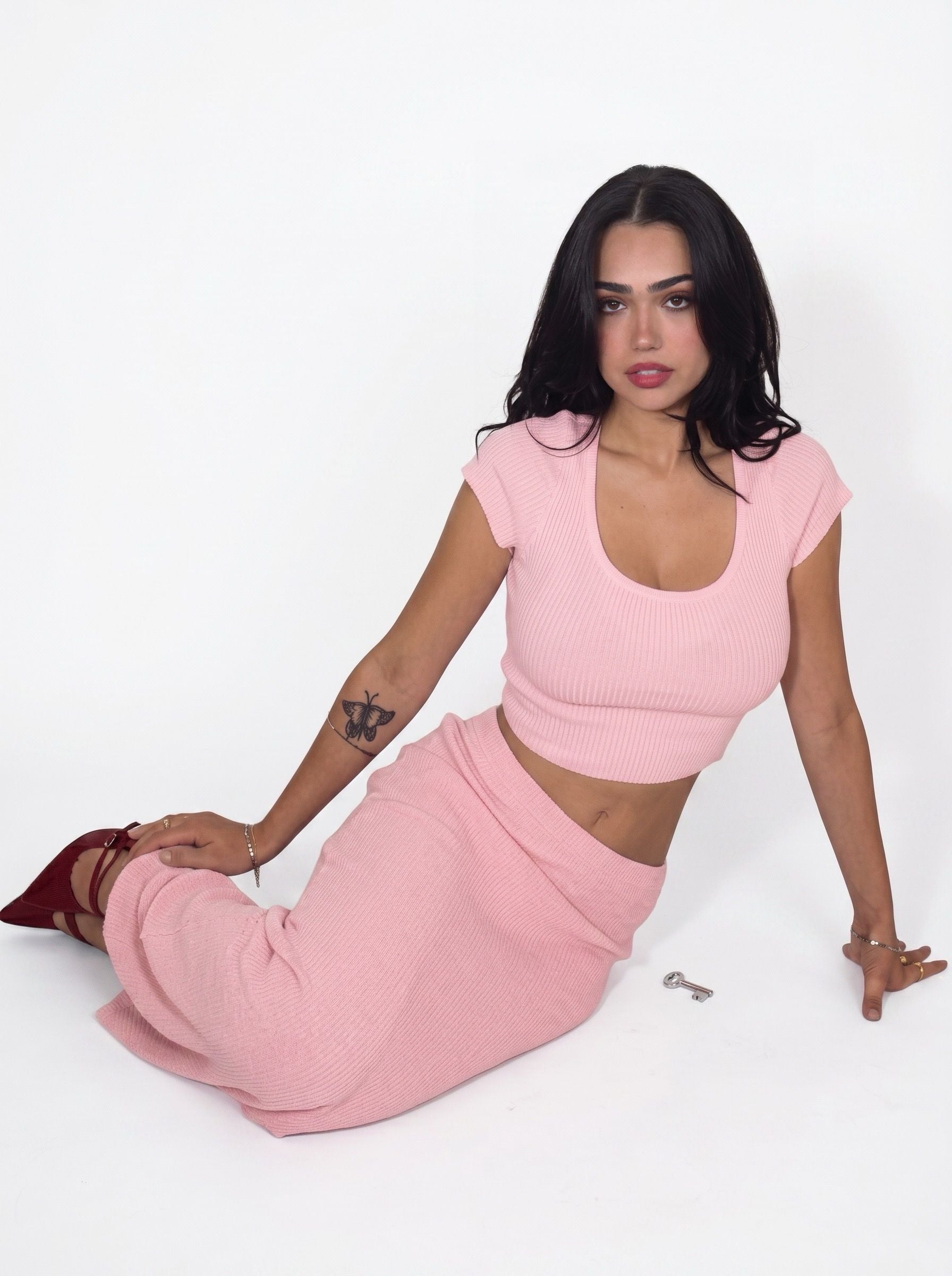 Woman sitting in matching pink rib knit scoop neck top and long skirt by TKHLA 
