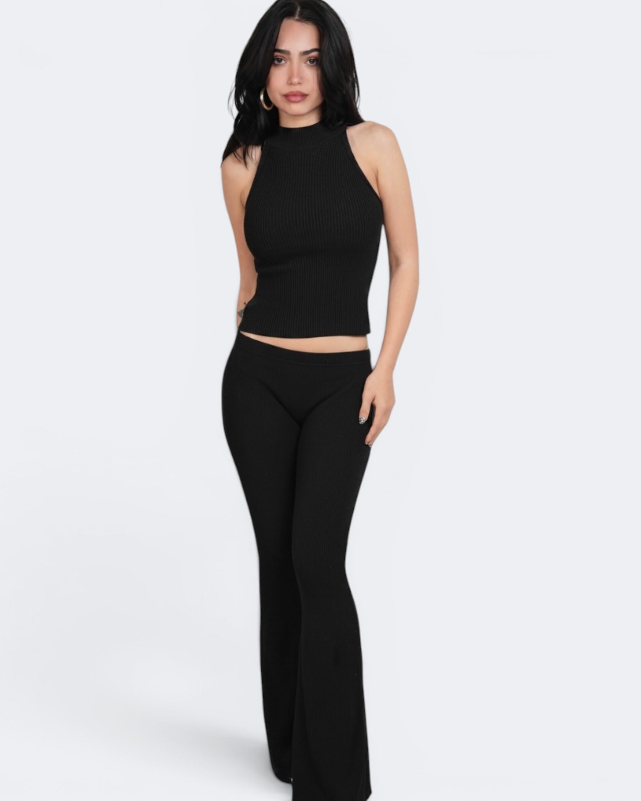 Woman wearing a black sleeveless top and black pants on a white background