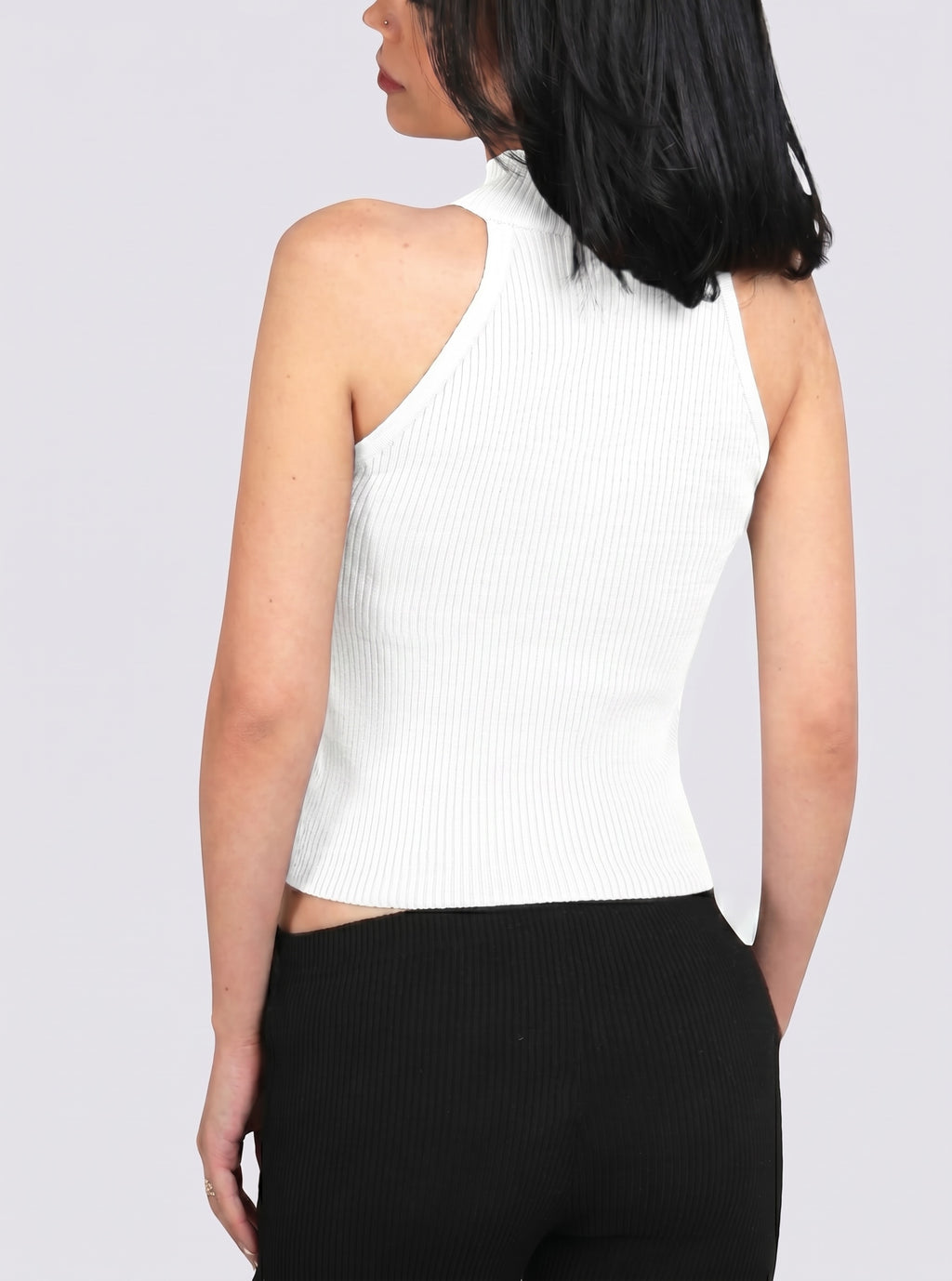 Woman wearing white rib knit mock neck shell with black Capri by TKHLA 