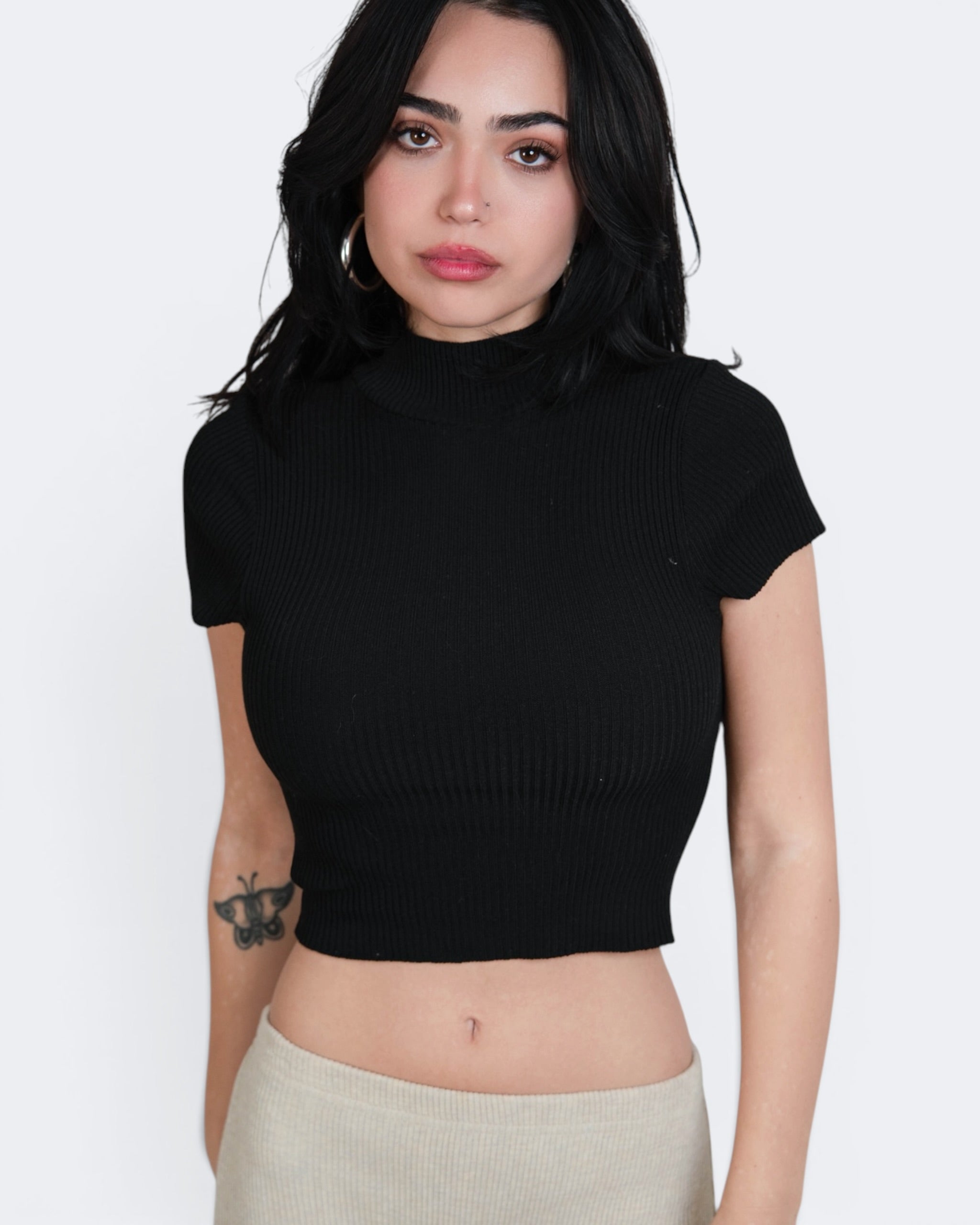 Woman wearing a black ribbed crop top against a white background