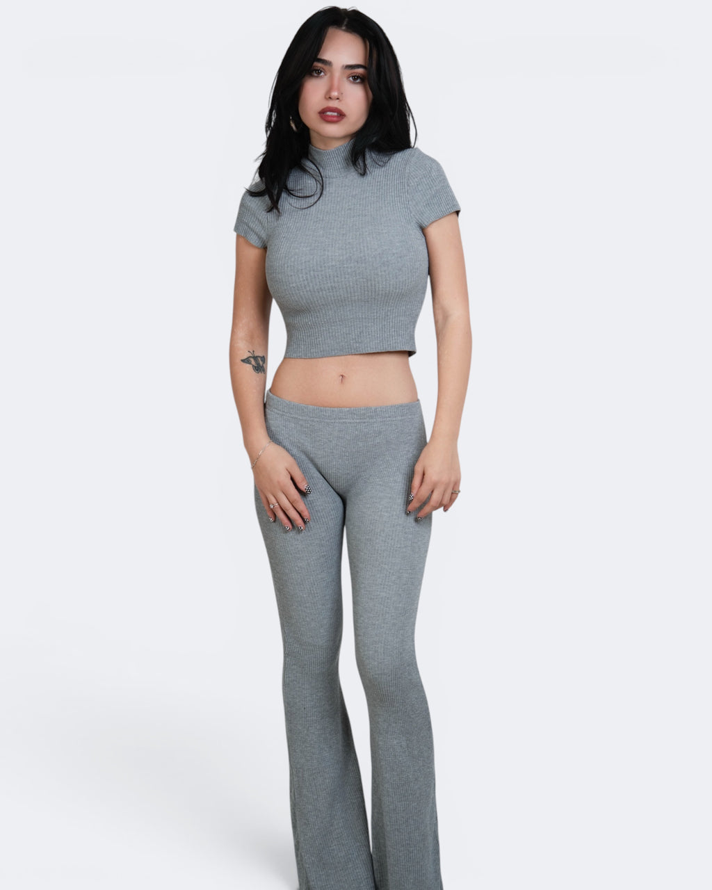 Woman wearing a gray knit outfit on a white background