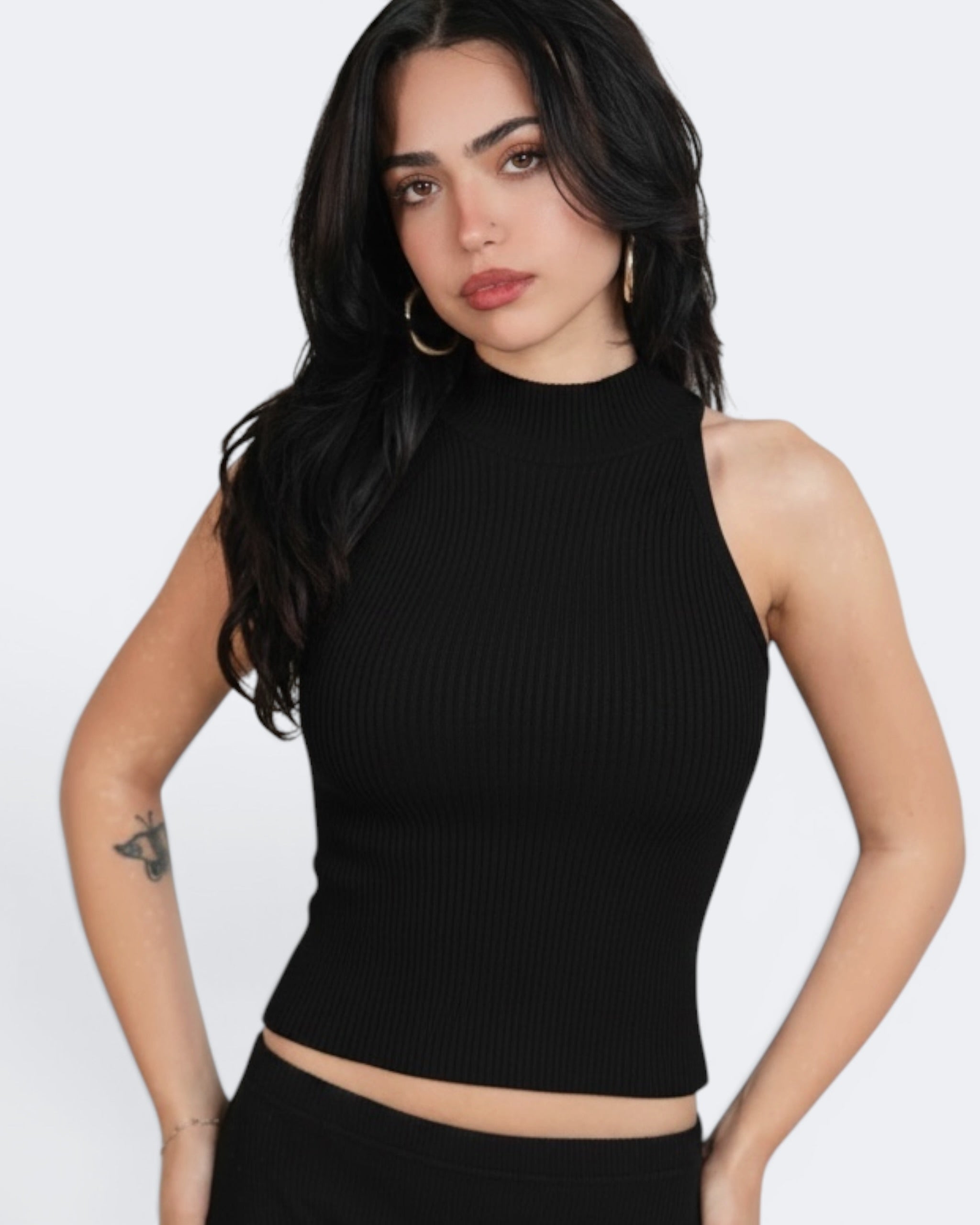 Woman wearing a black ribbed tank top against a white background