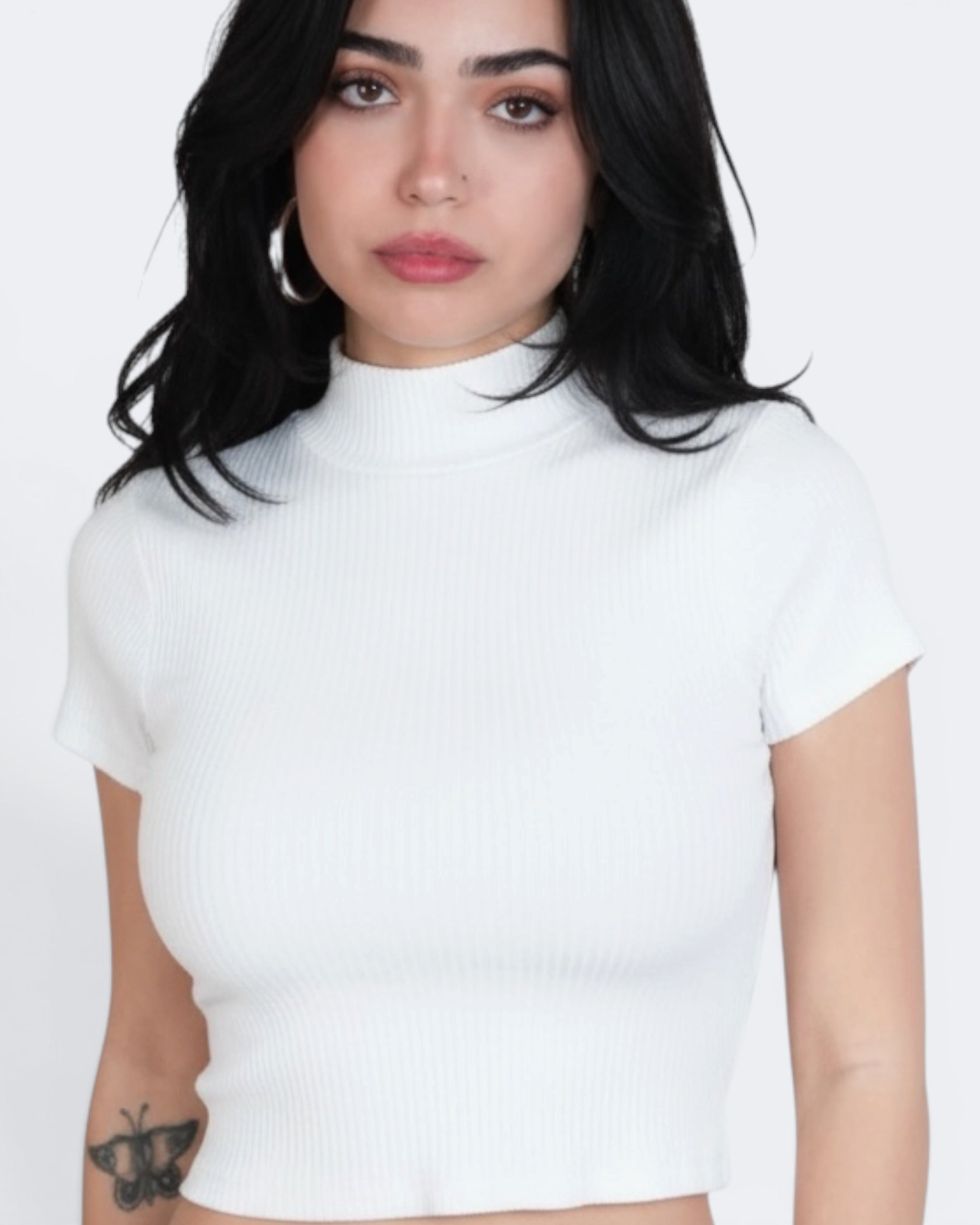 Person wearing a white short-sleeve top against a plain background