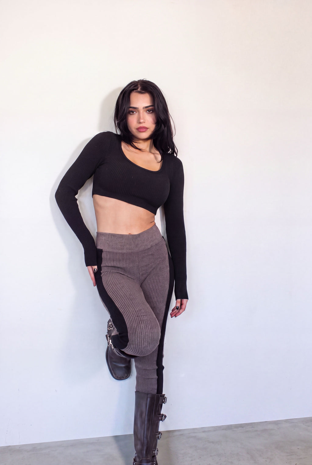 Woman wearing rib knit plum brown leggings with black side panel with black  crop long sleeve scoop neck top by TKHLA 