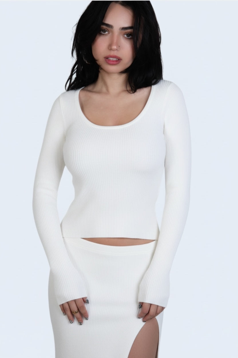 Woman wearing a white long-sleeve top and skirt set against a light gray background