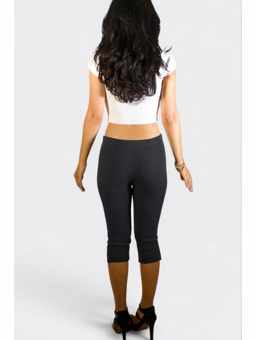 Person wearing a white crop top and black capri pants on a white background