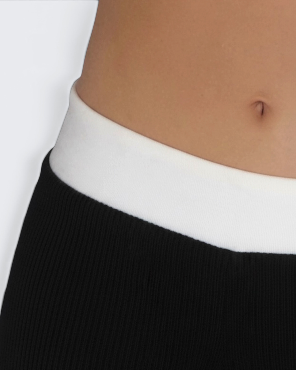 Close-up of a person wearing a black hot pant with a white waistband.
