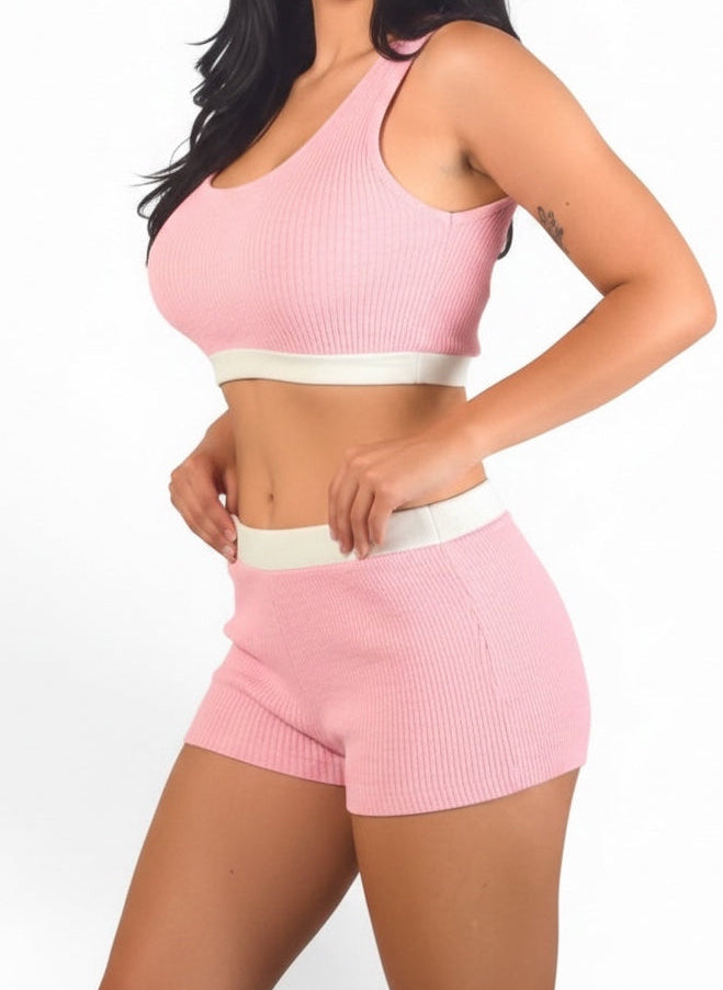 Woman wearing a pink ribbed sports bra and shorts set on a white background
