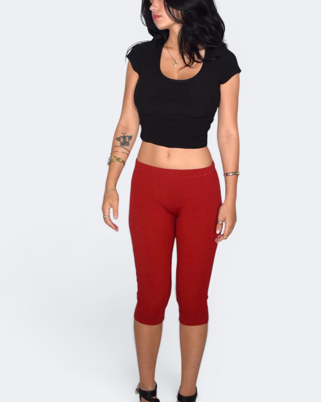 Person wearing a black crop top and red capri pants on a white background