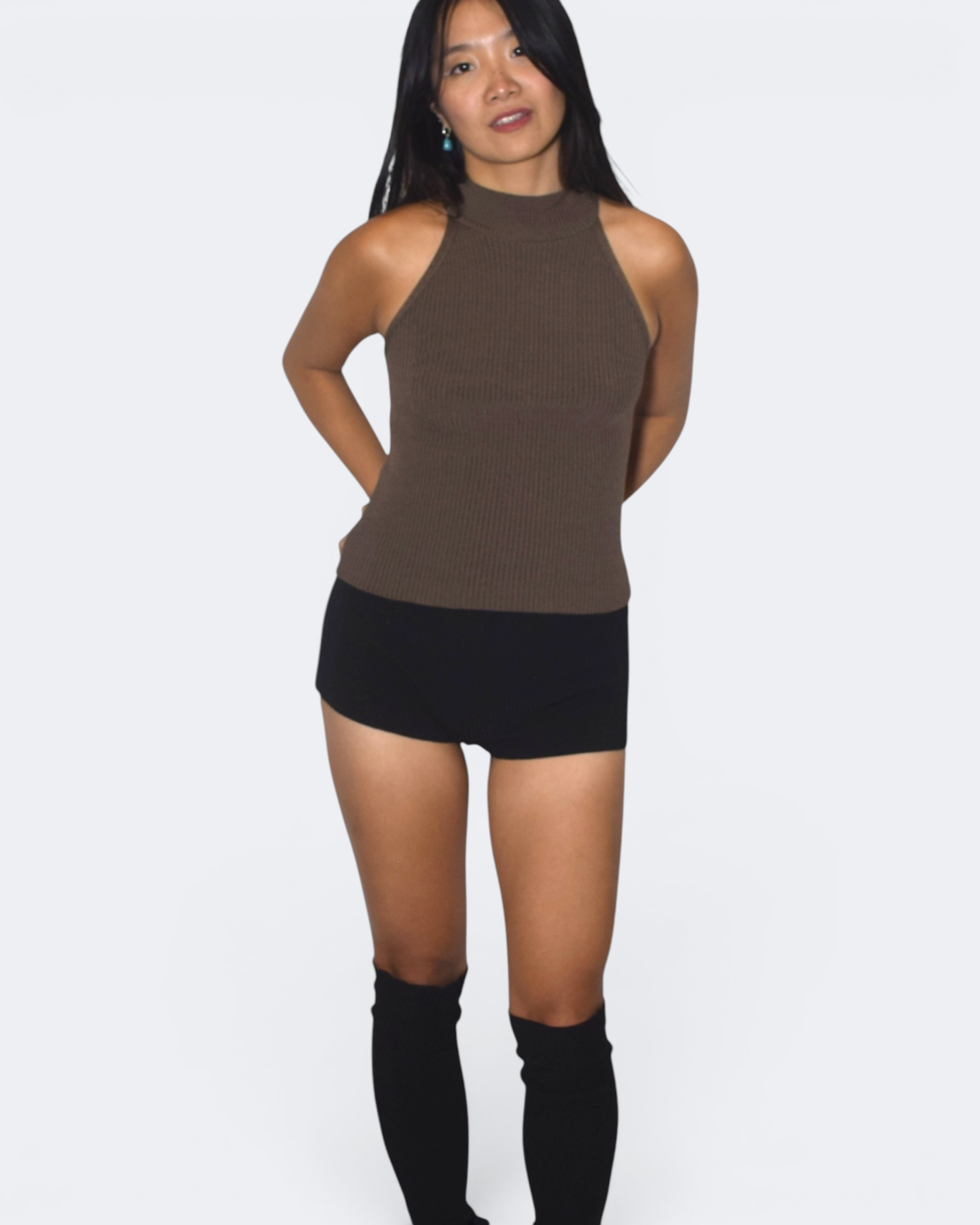Woman wearing a brown sleeveless top and black shorts on a white background